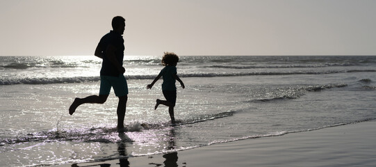 Fototapeta na wymiar Silhouette of father and son run on summer beach outdoor, banner poster with copy space, father and son silhouettes running having fun and feel freedom on summer beach, summer vacation