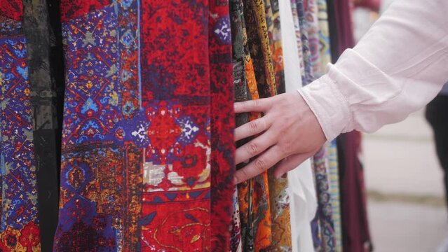 Woman chooses clothes dress in Turkish Bazaar shopping mall. woman's hand touching textile