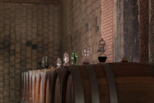 Old wine cellar, large wooden barrels for wine aging with glass siphons in bungholes