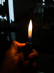 Human hand igniting a lighter with dark background