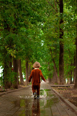 a little boy runs and jumps in the puddles during the summer rain.Childhood.