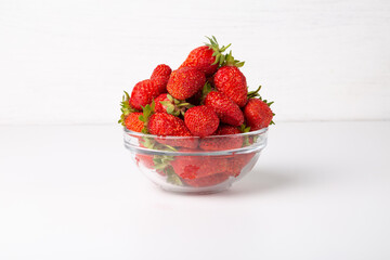 Red ripe strawberries in a cup on a table on a white background.