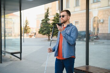 Blinded man waiting for bus at a bus station