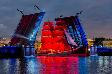 Scarlet sails ship between open Palace bridge parts during White nights festival, Saint Petersburg, Russia