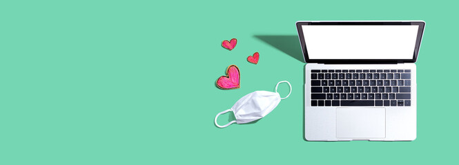 Laptop computer with a facial mask and hearts - overhead view