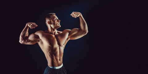 Fototapeta na wymiar bodybuilder posing. Beautiful sporty guy male power. Fitness muscular body. Isolated on black background
