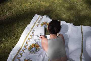 woman reading magazine in nature on a sunny day, spending time in nature self-development