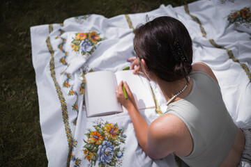 woman lying down in the forest on a sunny day writing notes in a notebook