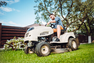 Professional gardener riding a lawn tractor and mowing grass, lawn