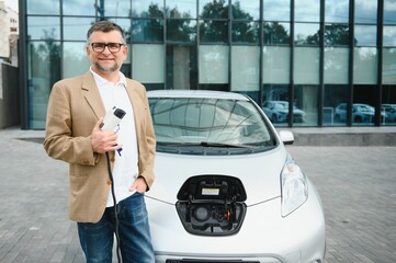 a businessman charges an electric car