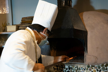 Chef Italiano preparando una pizza en el horno de lena.