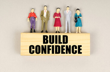 On the block with the inscription - Build Confidence are miniature figures of people.