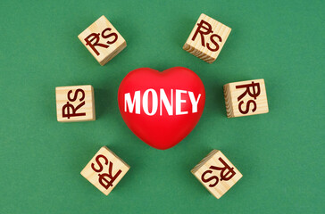 On a green surface, a heart with the inscription - money and cubes with the symbol of the Indonesian rupiah