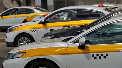 White and yellow taxis stand in a tight traffic jam on a hot sunny day. The theme of saturated...