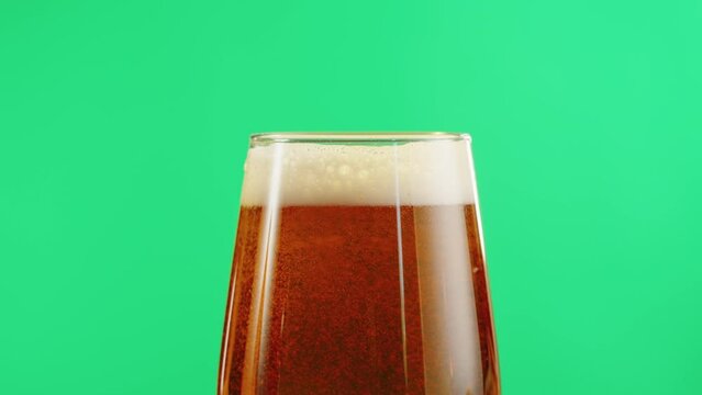 Foamy beer in glass close-up. Alcohol golden beer drink in mug. Fresh pale ale on green chroma key background.  - Powered by Adobe