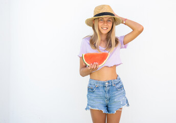 Young pretty girl wearing straw hat holding a slice of watermelon in hands and smiling happy, over white background outdoors. Summertime concept.