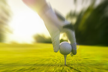 Closeup of golfer wearing glove placing golf ball on a tee at golf course with motion blur effect