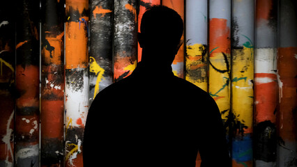 Man looking at art painting in museum, rear view. Concept. Male silhouette looking at rotating tubes covered by colorful brush strokes in dark room. - obrazy, fototapety, plakaty