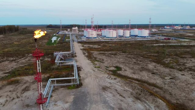 The drone flies around the oil storage tank, oil and gas reserves of Russia. Oil and gas industry in the world economy An oil and gas torch burns with a bright flame and burns excess gas.