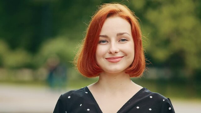 Close up outdoors portrait of human female face caucasian young girl redhead woman lady smiling outside nodding head yes answers approval sign agree positive agreement approval support posing flirting