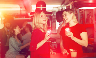 Two young women with cocktails having fun on party at nightclub. High quality photo