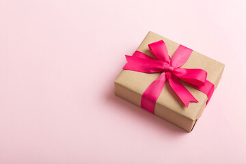 Wrapped christmas or other holiday handmade present in craft paper with colored ribbon. Present box, decoration of gift on table, top view with copy space