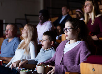 Spectators eating popcorn and watching horror movie in the cinema