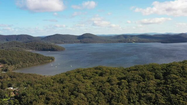 Slow aerial over trees fly to Wallis lake in Booti Booti NP of Austrlaia as 4k.
