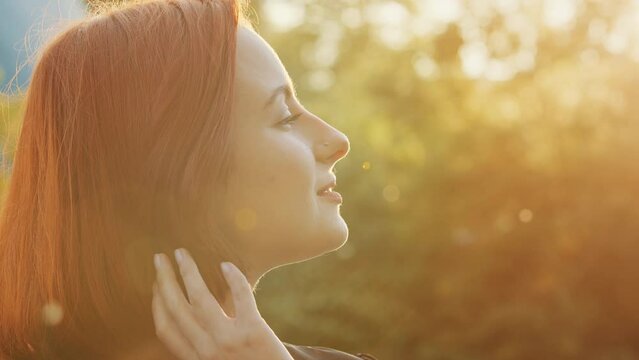 Close up beautiful female profile face redhead teen girl woman with short trendy hairstyle attractive smiling young model fix hair posing outdoors look at sunset sky enjoy sunbeams in summer weather