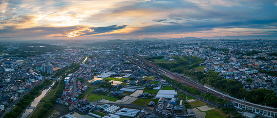 Aerial panorama: Sunrise over river and train tracks through sprawling suburban rural area - 513405512