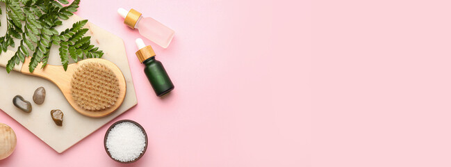 Composition with bottles of essential oil, sea salt and massage brush on pink background with space...