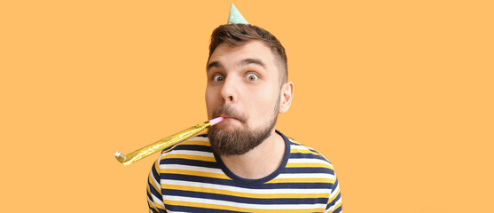 Funny man with party whistle celebrating Birthday on orange background
