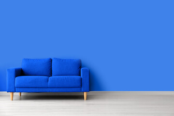 Comfortable sofa near blue wall in interior of room
