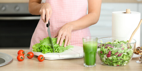 Obraz na płótnie Canvas Young woman making fresh salad in kitchen