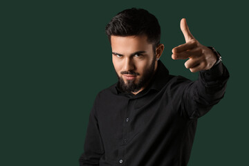 Bearded man pointing fingers gun gesture on color background