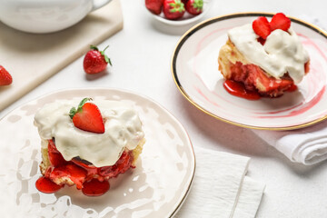 Plates with strawberry cinnamon rolls and cream on white background