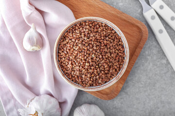Bowl with buckwheat grains on grey table