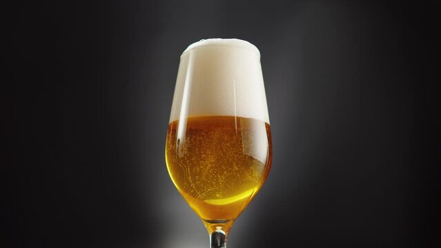 Foamy beer in glass close-up. Alcohol golden beer drink in mug. Fresh pale ale on black background. 
