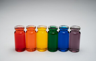 hilera de botellitas con agua coloreada multicolor, arcoiris con fondo blanco 