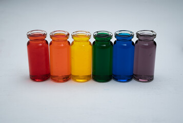hilera de botellitas con agua coloreada multicolor, arcoiris con fondo blanco 