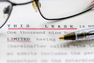 Close up of a lease for a property shown with eye glasses. A legal document for long term rental or ownership of a business premise or home.