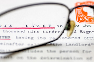 Close up of a lease for a property shown with eye glasses. A legal document for long term rental or ownership of a business premise or home.