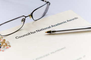A United Kingdom higher education certificate issued by the Council for National Academic Awards shown with a pair of glasses and a pen.