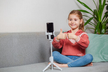 Small blonde blogger girl, an influential person, communicates with subscribers, conducts a live broadcast with a cat, looks at the smartphone screen at home. When taking a selfie, call your friends.