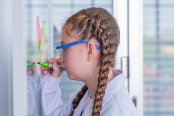 schoolgirl study science subjects and use marker write on board glass