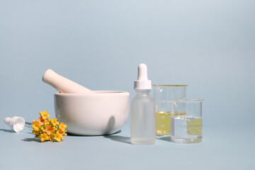 Natural cosmetic, skincare, and beauty product with oil, pestle, and mortar on blue background. clean beauty concept.