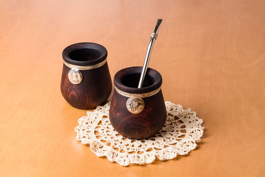 Tazas de madera tallada y plata cincelada para beber infusi&oacute;n de yerba mate, sobre peque&ntilde;o mantel tejidos