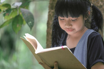 Fototapeta premium Child little girl reading read book in park under tree.
