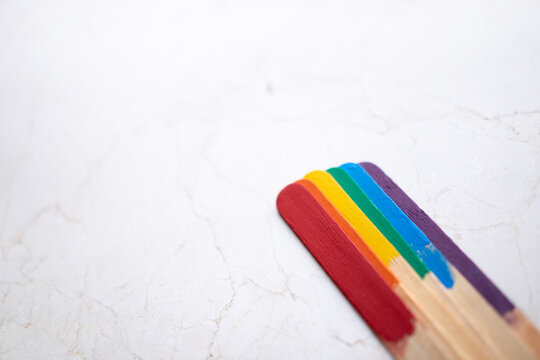 seis palos de madera, batelenguas, arcoiris multicolor sobre base de m&aacute;rmol clara