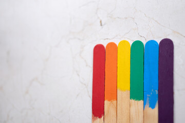 seis palos de madera, batelenguas, arcoiris multicolor sobre base de mármol clara